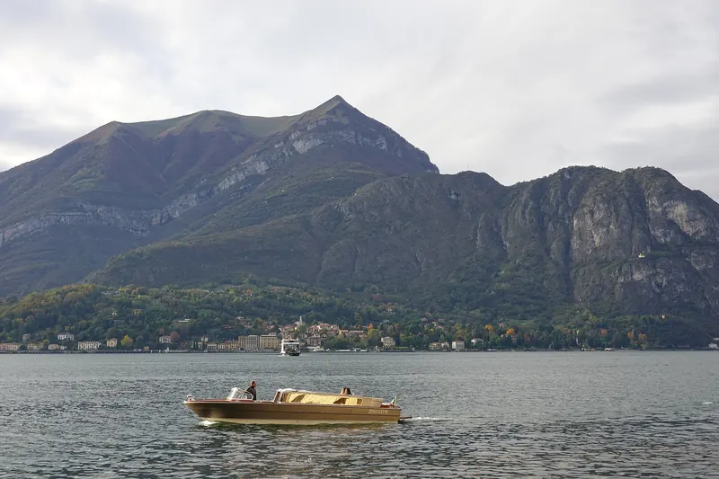 Mountains rising above Lake Como at Bellagio, with a wooden boat on the water